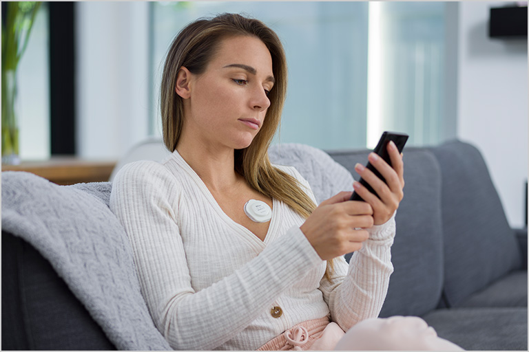 Person on couch with Radius T temperature monitor looking at smartphone.